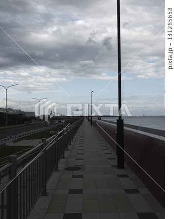 海沿いの長い歩道と街灯、遠くの滑走路へ向かう着陸直前の飛行機 131285658