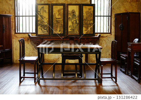 Antique old wooden table and chair furniture of Chinese style in vintage and rustic grunge concrete wall in living room with natural sunlight in Bangkok of Thailand Antique old wooden table and chair furniture of Chinese style in vintage and rustic grunge concrete wall in living room with natural sunlight in Bangkok of Thailand 131286422