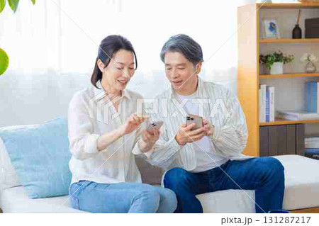 スマホ ソファーでくつろぐミドル夫婦 スマホ ソファーでくつろぐミドル夫婦 131287217