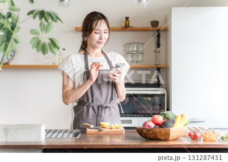 家のキッチン・ダイニングでスマホのアプリを使うアジア人女性 131287431