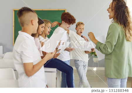 Young school children standing with their young female teacher having music lesson. 131288346