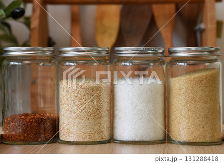 A clear jar that holds seasonings for cooking inside. On the wooden table in the kitchen A clear jar that holds seasonings for cooking inside. On the wooden table in the kitchen 131288418