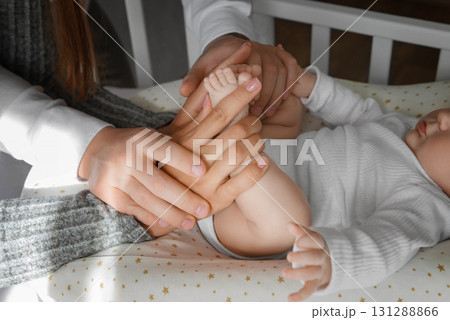 Fathers and mothers hands holding babys feet. Closeup of Hands Holding Babys Feet. 131288866