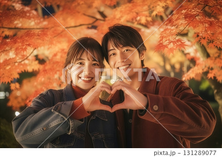 紅葉を背景に手でハートマークをつくるカップル 131289077