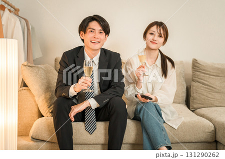 夜,帰宅後にソファに座りながらシャンパンを飲む若いアジア人夫婦,カップル 131290262