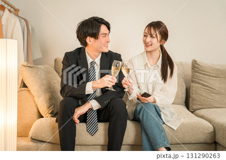 夜,帰宅後にソファに座りながらシャンパンを飲む若いアジア人夫婦,カップル 夜,帰宅後にソファに座りながらシャンパンを飲む若いアジア人夫婦,カップル 131290263