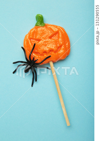 Halloween lollipops shaped like a pumpkin with decorative spider on blue background. Vertical photo 131290555