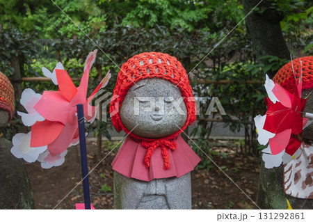 Stone Jizo statue wearing red knitted hat and bib in Japanese garden at Tokyo, Japan Stone Jizo statue wearing red knitted hat and bib in Japanese garden at Tokyo, Japan 131292861