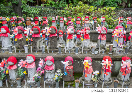 Jizo statues wearing red hats and bibs at Japanese temple garden with flowers at Tokyo, Japan Jizo statues wearing red hats and bibs at Japanese temple garden with flowers at Tokyo, Japan 131292862