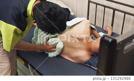 高齢者の清拭を行うアジア人介護士 131292980