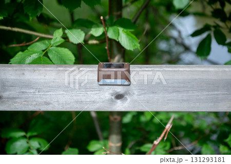 Small outdoor solar lamp on wooden railing in nature 131293181
