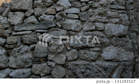 An ancient stone wall made up of gray stones of different sizes.  131293527