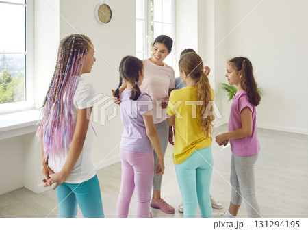 Happy dance teacher talking with her kids girls at the end of class in choreography studio. Happy dance teacher talking with her kids girls at the end of class in choreography studio. 131294195