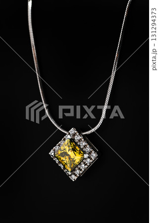 A yellow diamond necklace sits on a black surface A yellow diamond necklace sits on a black surface 131294373