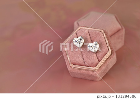 A pair of diamond earrings are displayed in a pink velvet box A pair of diamond earrings are displayed in a pink velvet box 131294386