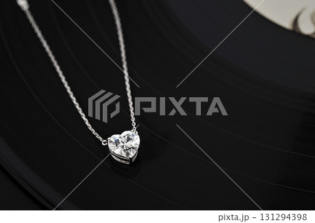 A necklace with a heart pendant is on a black record A necklace with a heart pendant is on a black record 131294398