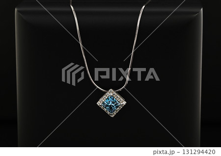 A blue and white necklace sits on a black surface 131294420