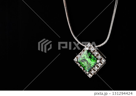 A green gemstone pendant is displayed on a black background 131294424
