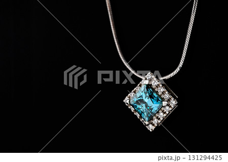 A blue diamond necklace sits on a black surface A blue diamond necklace sits on a black surface 131294425