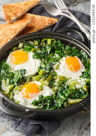 shakshuka green sauce loaded with fresh herbs, spinach, and spices is the perfect foil for rich, runny eggs closeup on the pan. Vertical shakshuka green sauce loaded with fresh herbs, spinach, and spices is the perfect foil for rich, runny eggs closeup on the pan. Vertical 131294438