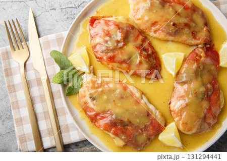 Saltimbocca chicken cutlets topped with prosciutto and sage leaves are pan-seared, then served in a simple white wine butter sauce closeup on the plate. Horizontal top view Saltimbocca chicken cutlets topped with prosciutto and sage leaves are pan-seared, then served in a simple white wine butter sauce closeup on the plate. Horizontal top view 131294441