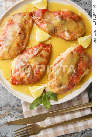 Chicken Saltimbocca combines thinly sliced pan-seared chicken cutlets, salty prosciutto, and sage leaves in a white wine butter sauce closeup on the plate. Vertical top view 131294444
