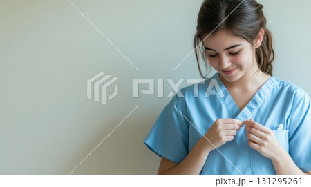 Minimalistic scene of healthcare worker in blue scrubs adding thank-you badge, expressing appreciation and professionalism, ideal for medical campaigns and recognition visuals. 131295261