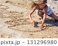 Little girl drawing hopscotch in the sand on a sunny beach 131296980