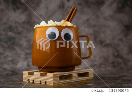 Halloween funny faces eyes on cup of beverage Autumn hygge Orange Cup of warm coffee. Cozy fall still life dark background. Thanksgiving holiday Halloween funny faces eyes on cup of beverage Autumn hygge Orange Cup of warm coffee. Cozy fall still life dark background. Thanksgiving holiday 131298076