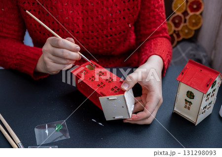 Process of preparing for Christmas and New Year eve. Unrecognizable woman in red sweater painting 3D craft wooden houses DIY. Responsible ecological zero waste handmade decoration. Children hobby Process of preparing for Christmas and New Year eve. Unrecognizable woman in red sweater painting 3D craft wooden houses DIY. Responsible ecological zero waste handmade decoration. Children hobby 131298093