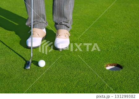 Golf green hole course man putting short ball 131299382