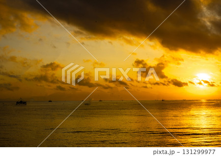 Tranquil dawn seascape. Beautiful sunrise over the sea, featuring traditional fishing boats catching the first light. Tranquil dawn seascape. Beautiful sunrise over the sea, featuring traditional fishing boats catching the first light. 131299977