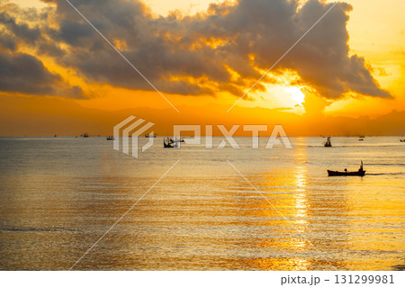Tranquil dawn seascape. Beautiful sunrise over the sea, featuring traditional fishing boats catching the first light. 131299981