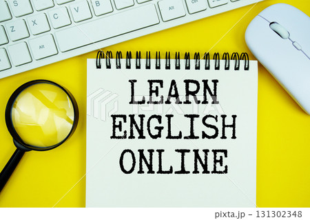 Notepad with the text "Learn English Online" and white keyboard, wireless mouse, magnifying glass on yellow background Notepad with the text "Learn English Online" and white keyboard, wireless mouse, magnifying glass on yellow background 131302348