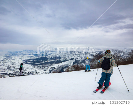 スキー場の山頂から雪景色を眺めながら滑走するスキーヤーたち (新潟県、南魚沼市、石打丸山) 131302719