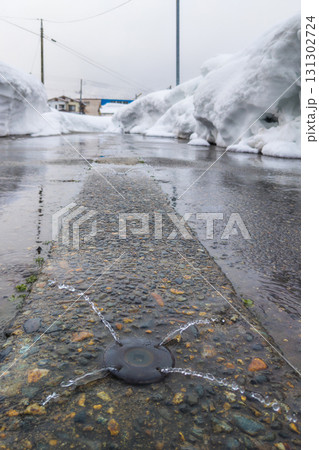 消雪パイプから地下水が噴き出す雪国の濡れた道路と高い雪の壁 (新潟県、南魚沼市、石打) 消雪パイプから地下水が噴き出す雪国の濡れた道路と高い雪の壁 (新潟県、南魚沼市、石打) 131302724
