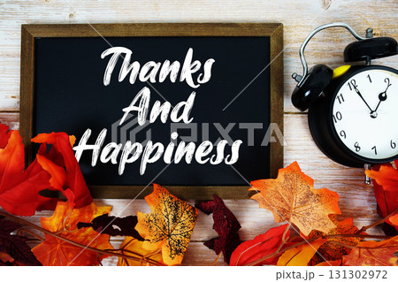 Thanks and Happiness text written on chalkboard with alarm clock and maple leaf decoration on wooden background Thanks and Happiness text written on chalkboard with alarm clock and maple leaf decoration on wooden background 131302972
