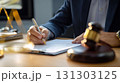 Cropped photo of a lawyer signing documents in court. The cropped view highlights the lawyer's hands, showcasing the significance of signing vital papers in the courtroom. 131303125