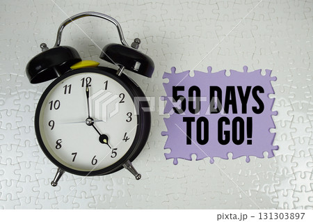 50 Days To Go! text with alarm clock on purple background 50 Days To Go! text with alarm clock on purple background 131303897
