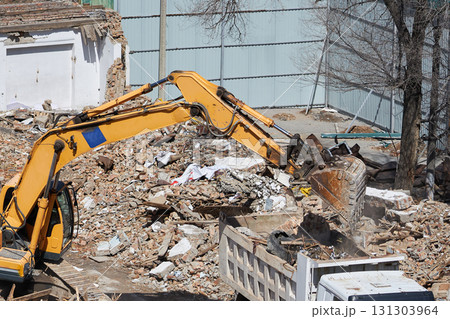 An excavator bucket dumps construction debris into the truck body An excavator bucket dumps construction debris into the truck body 131303964