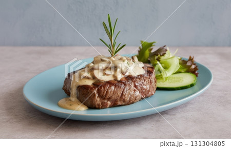Grilled steak with creamy mushroom sauce, fresh rosemary, and side salad on plate 131304805