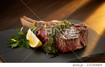 Perfectly seared ribeye steak with vibrant chimichurri sauce on a dark slate plate Perfectly seared ribeye steak with vibrant chimichurri sauce on a dark slate plate 131304809