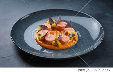 Meticulously plated gourmet salmon dish with vibrant orange puree and fresh purple basil 131305535