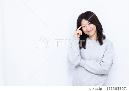 笑顔で頭を抱えて考えている女性 笑顔で頭を抱えて考えている女性 131305597