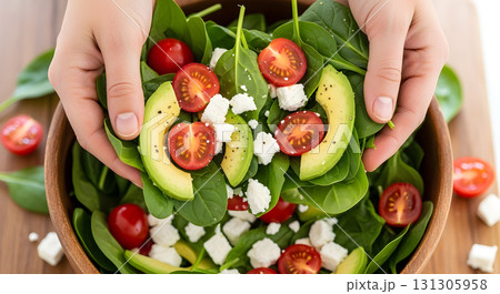 Hands holding a fresh salad with spinach, avocado, and tomatoes. Hands holding a fresh salad with spinach, avocado, and tomatoes. 131305958