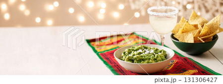 Cinco de Mayo table with guacamole, tortilla chips, festive drink in vibrant setting 131306427