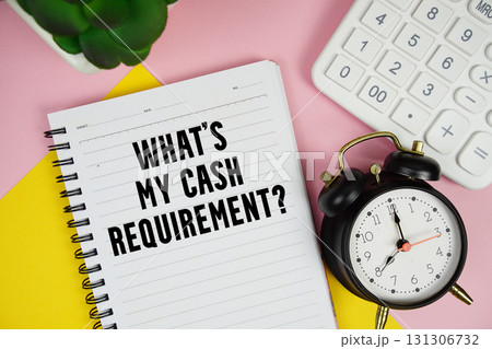 What's My Cash Requirement? text written on notepad with calculator and alarm clock on pink background 131306732