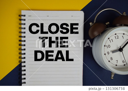 Close the Deal text written on notepad with alarm clock on yellow background 131306738
