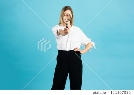 Studio portrait of woman with magnifying glass 131307050