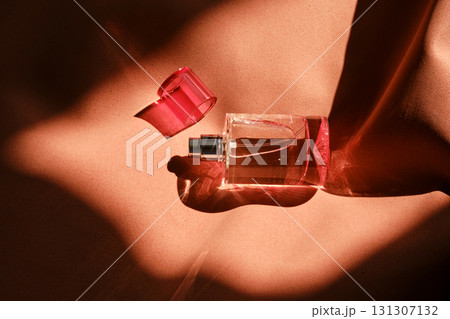 A pink perfume bottle on a soft reddish background. 131307132